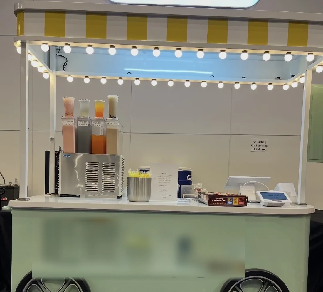 The Pearl & Mint Tea Co. mobile cart set up at an event, with drink dispensers and a full serving
counter