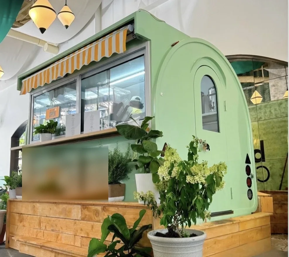 The mint green Pearl & Mint Tea Co. trailer with its striped awning and service window