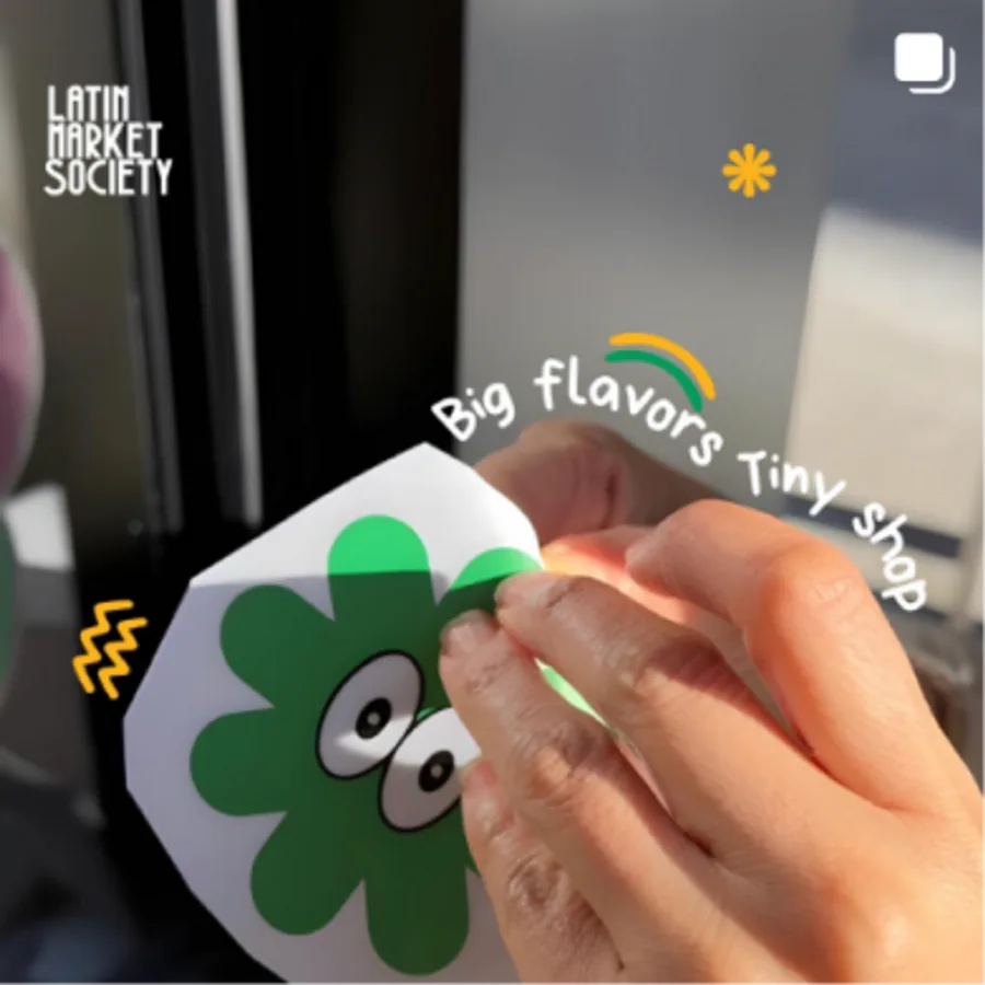 Peeling a Bandido Snack Club clover sticker — big flavors, tiny shop