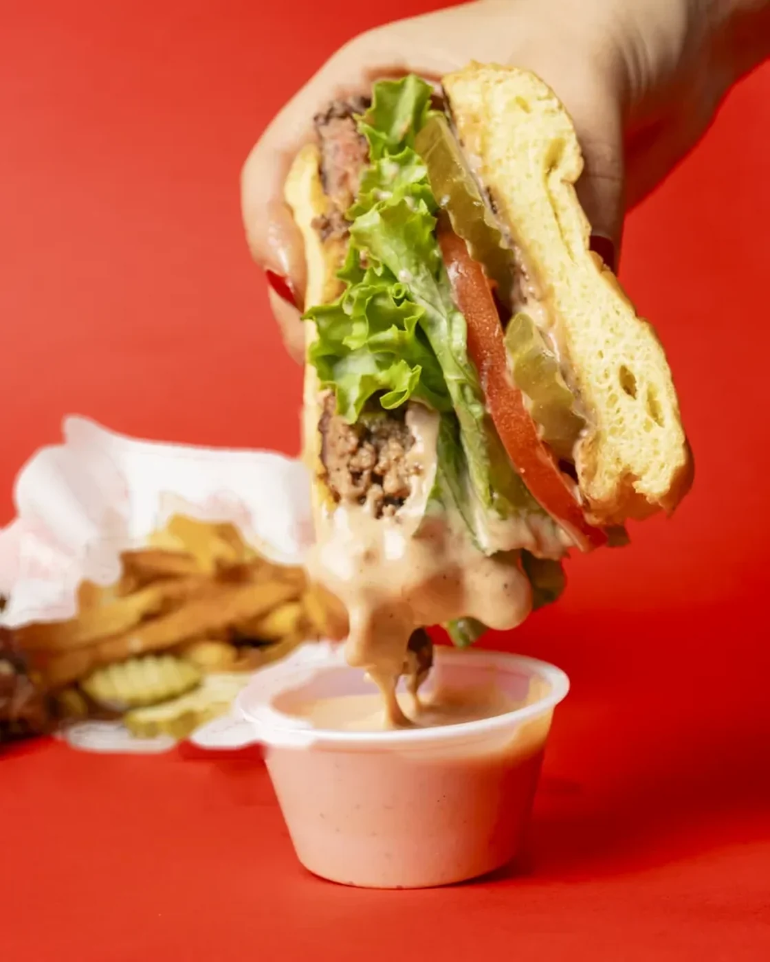A gloved hand laying cheese onto the patty