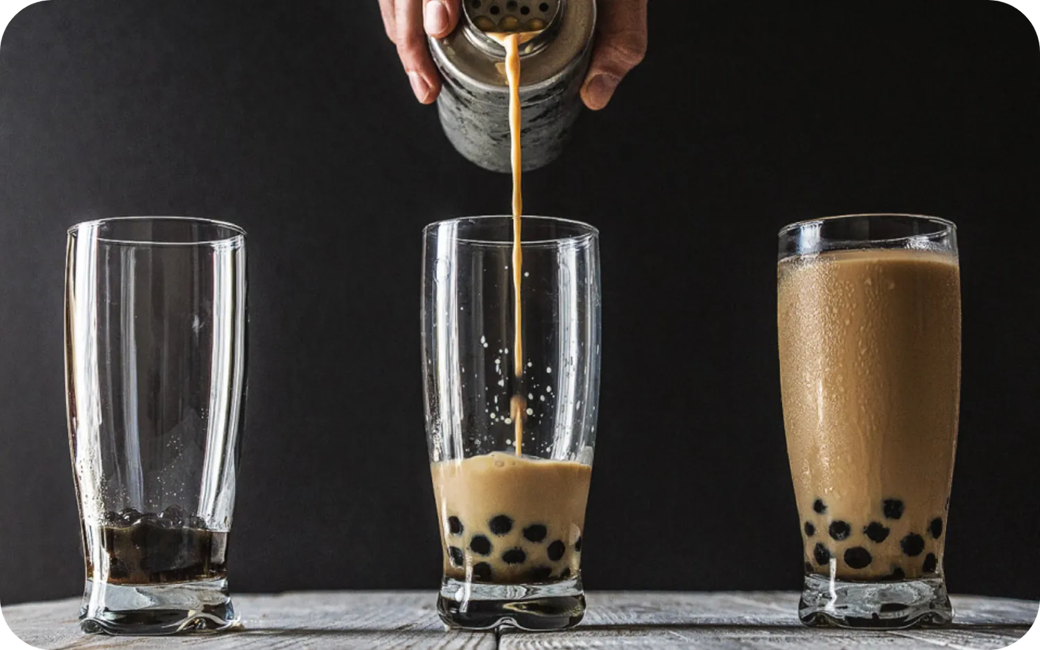 Brown sugar boba milk tea being poured over chewy tapioca pearls